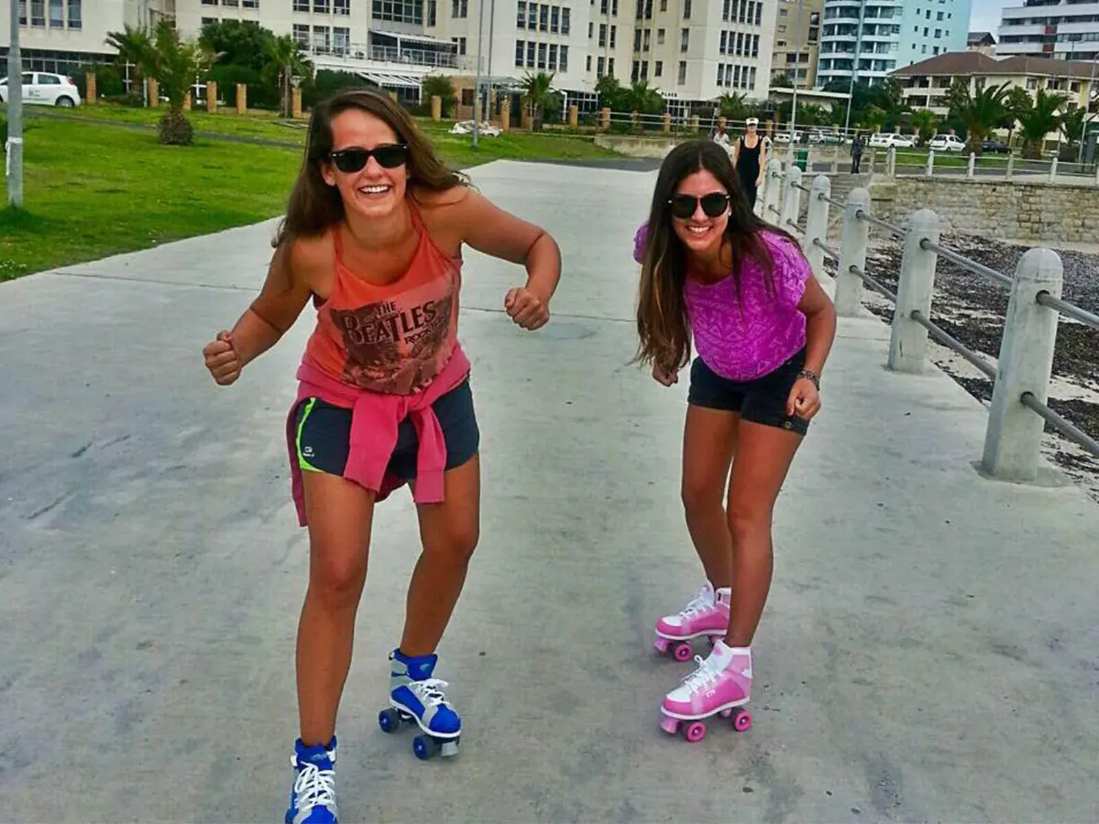 2 girls rolling skate in the city with blue and pink roller skates