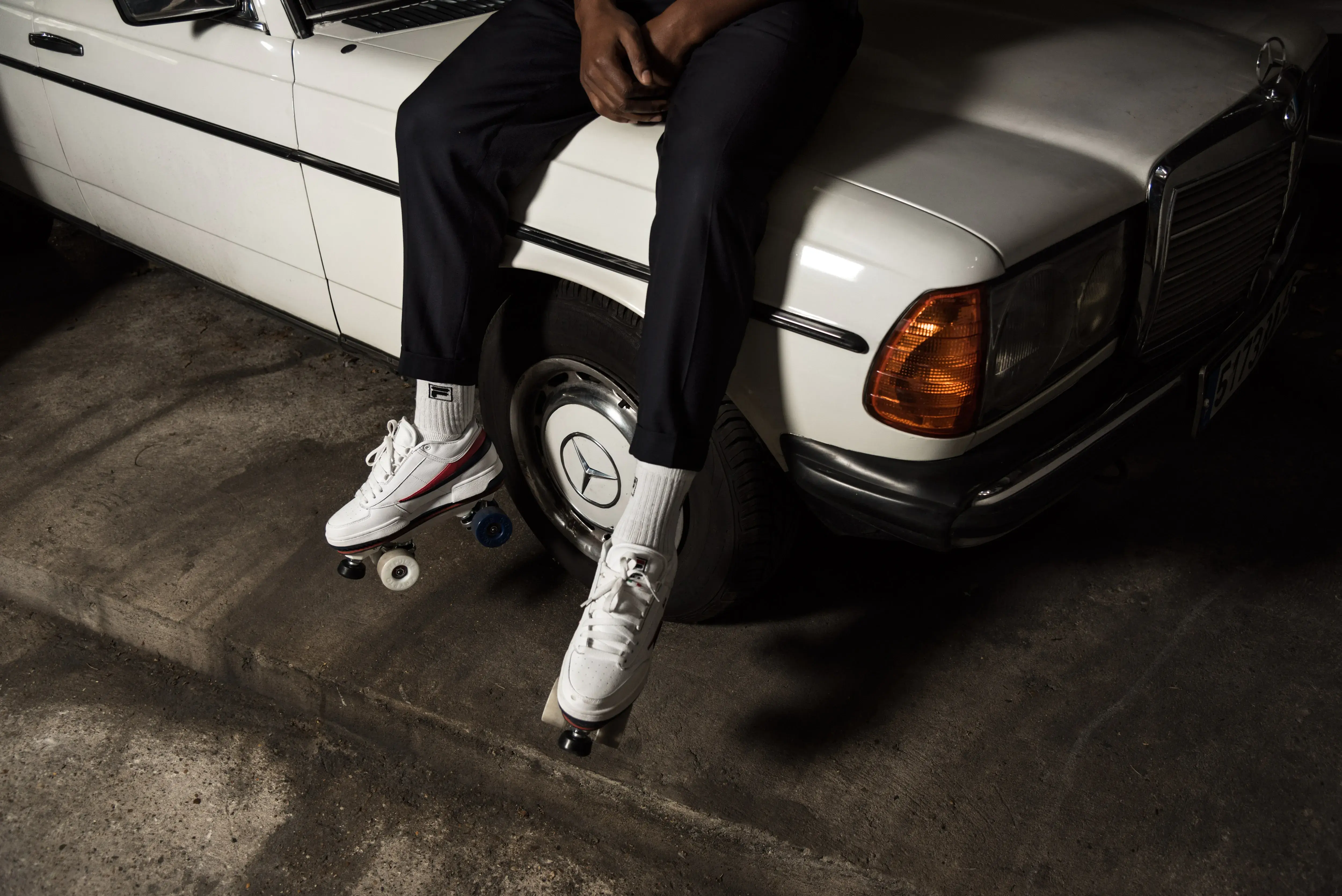 a man wearing roller skates by flaneurz sitting on a mercedes