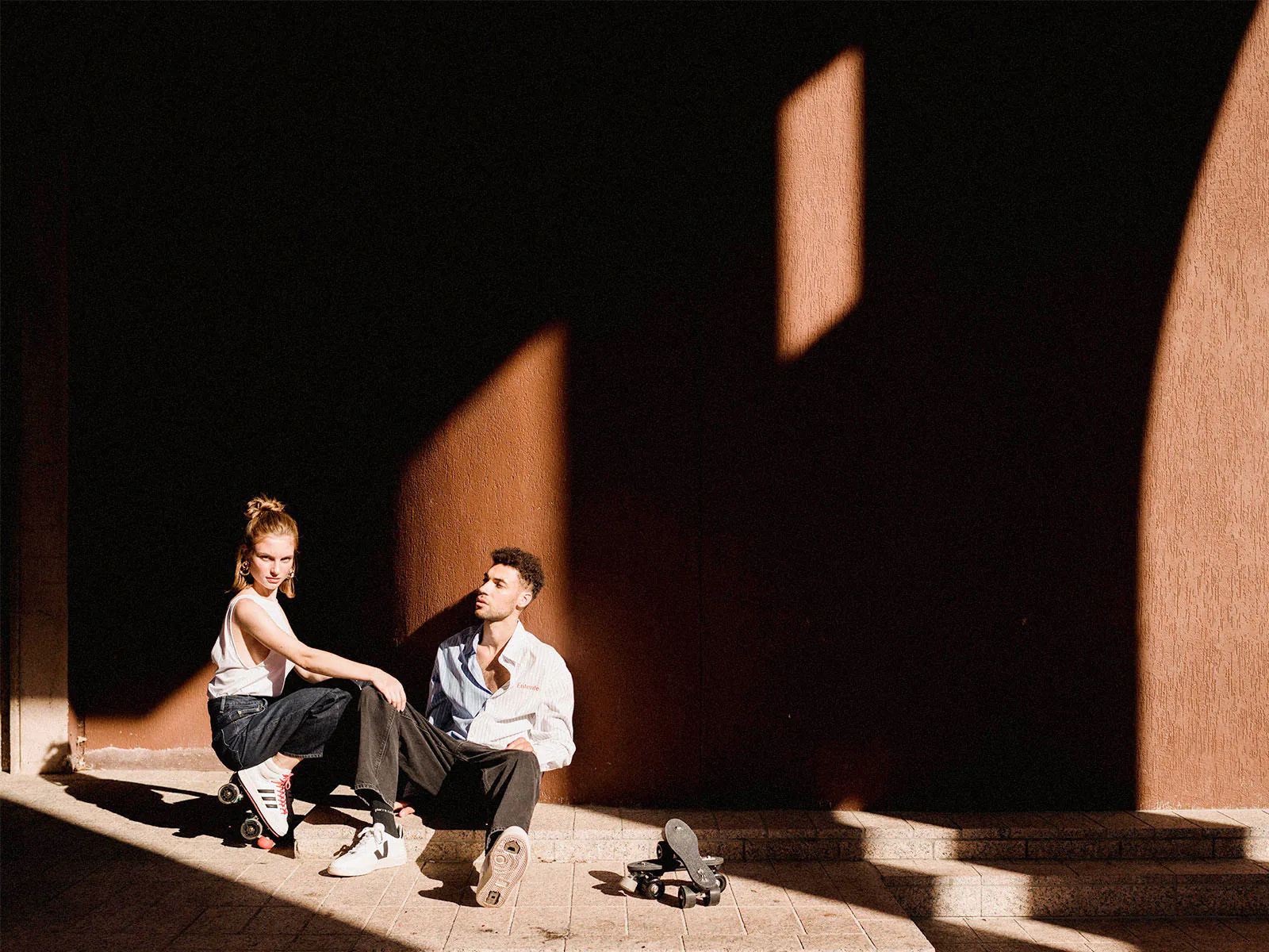 a man and a woman showing their roller skates (veja and adidas sneakers transformed by flaneurz )