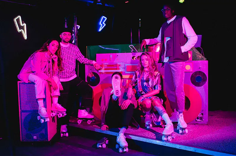a group of 5 people, 2 women and 3 men posing to show their roller skates