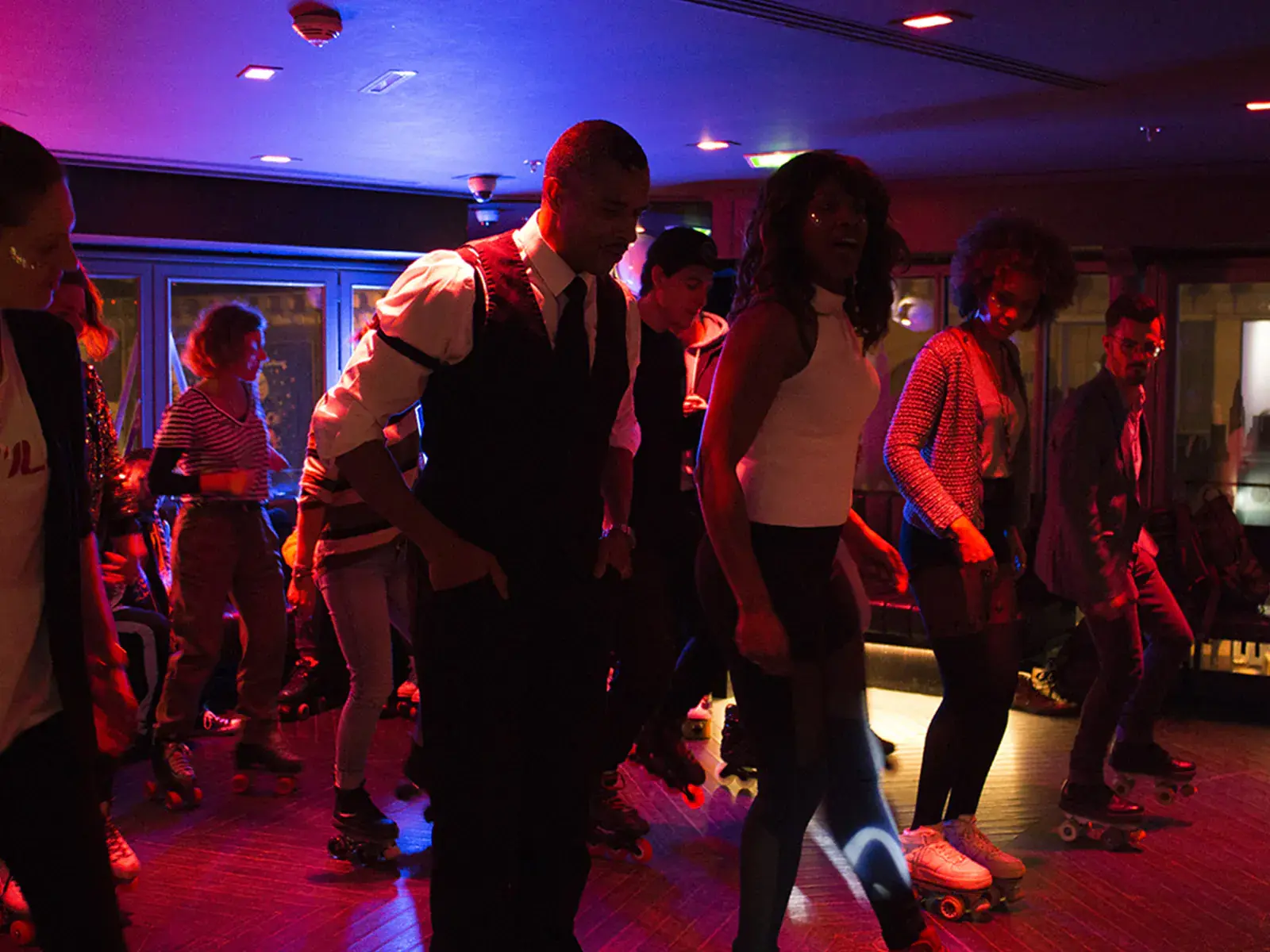 a group of people dancing around with their roller skates inside a club 